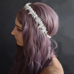 May include: A crystal crown headband with clear quartz points, worn by a person with purple hair.