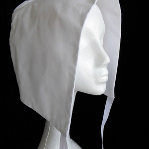 May include: A white fabric bonnet with a wide brim and a long tie. The bonnet is made of a soft, lightweight fabric and has a simple, elegant design.