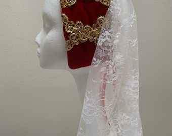 May include: A red velvet headband with gold embroidery and a white lace veil with pearl accents.
