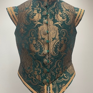 May include: A green and gold brocade vest with a high collar and short sleeves. The vest has a button-up front and gold trim around the edges.