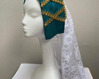 May include: A teal medieval-style headdress with gold trim and a white lace veil. The headdress is displayed on a mannequin head. The gold trim is in a decorative pattern. The veil is made of a delicate white lace.