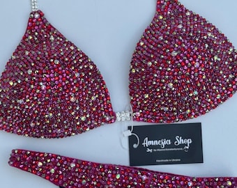 Op de afbeelding: Een roze bikini top en broekje met een zilveren ketting en strass steentjes. De bikini is handgemaakt in Oekraïne en wordt verkocht door Amnesia Shop.