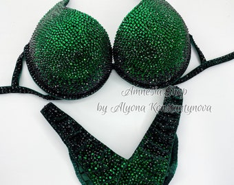 May include: A green competition bikini with a V-shaped bottom and a halter top. The bikini is covered in rhinestones.