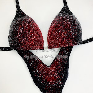 May include: Black and red competition bikini with a gradient design. The bikini is covered in rhinestones. The text "Amnesia Shop by Alyona Konstantinova" is printed on the bottom of the bikini.
