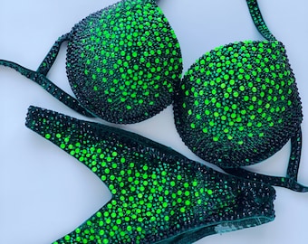 May include: A green and black bikini with a sparkly design. The bikini is covered in small green and black rhinestones.