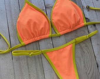 May include: A bright orange bikini with a yellow trim. The top is a triangle style with adjustable straps. The bottom is a cheeky style with a thin strap.