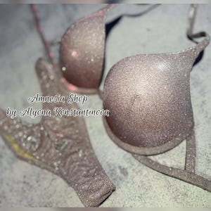 Puede incluir: Un conjunto de sujetador y braguita de color rosa claro brillante con un diseño delicado. El sujetador tiene un escote pronunciado y tirantes ajustables. La braguita tiene una cintura baja y un ribete de encaje. El conjunto está hecho de una tela suave y cómoda.