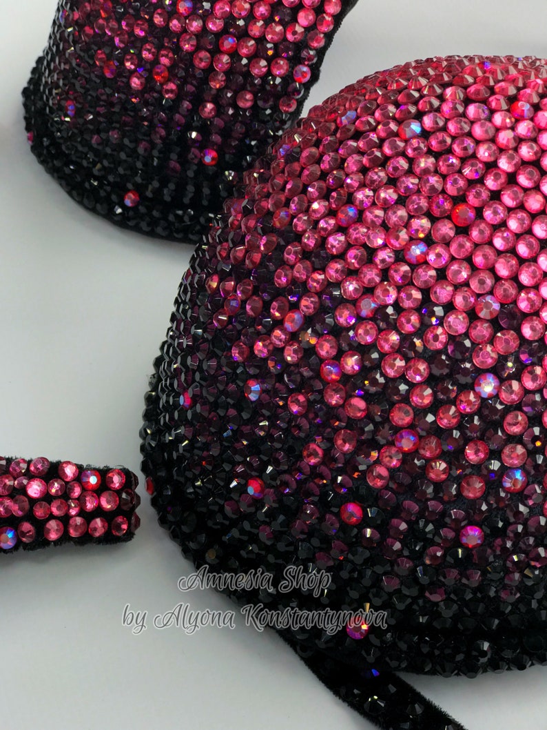 May include: A black and pink ombre bra with rhinestones. The bra is decorated with a gradient of pink rhinestones that fade to black. The bra is labeled "Amnesia Shop by Alyona Konstantynova".