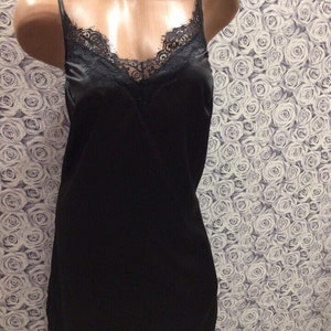 May include: A black satin slip dress with a lace trim around the neckline and hem.