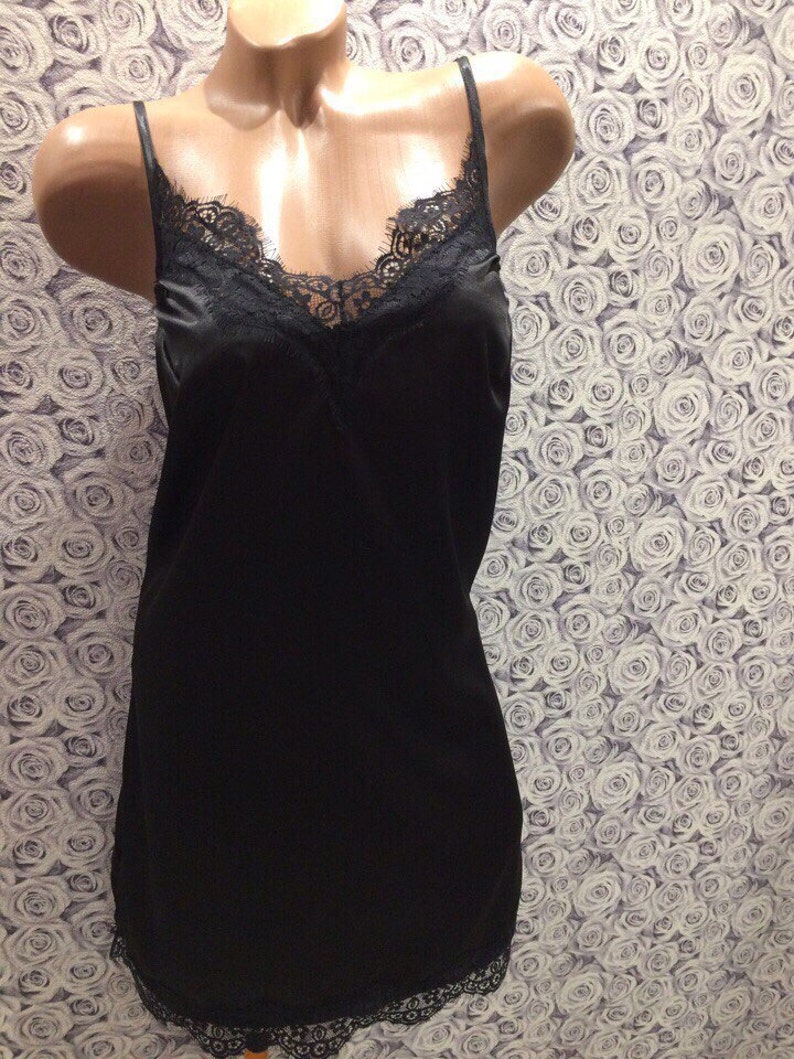 May include: A black satin slip dress with a lace trim around the neckline and hem.