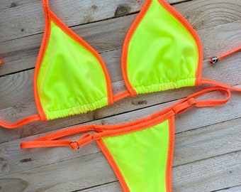 May include: A neon yellow bikini with orange trim. The top is a triangle style with adjustable straps and the bottom is a cheeky style.
