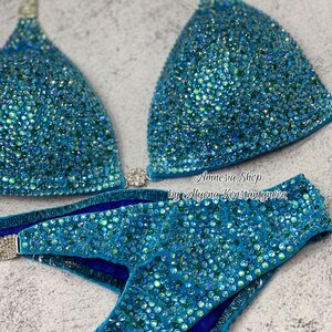 May include: A turquoise blue bikini with crystal embellishments. The bikini top has a halter style and the bottom is a high-cut style. The bikini is made of a soft, stretchy fabric and is perfect for a competition or special occasion.  Amnesia Shop by Alyona Konstantynova.
