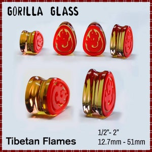 May include: Gorilla Glass Tibetan Flames ear plugs. The plugs are clear with a red flame design. Sizes range from 12.7mm to 51mm.