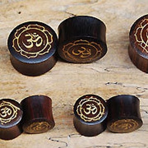 May include: Set of six wooden ear gauges with a brown finish and a gold Om symbol carved into the front.