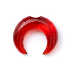 May include: Red crescent shaped glass ear gauge plug.