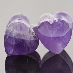 May include: Two purple amethyst heart-shaped plugs. The plugs are smooth and polished.