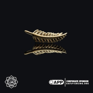 May include: Gold feather-shaped earring with a detailed design. The earring is shown against a black background.