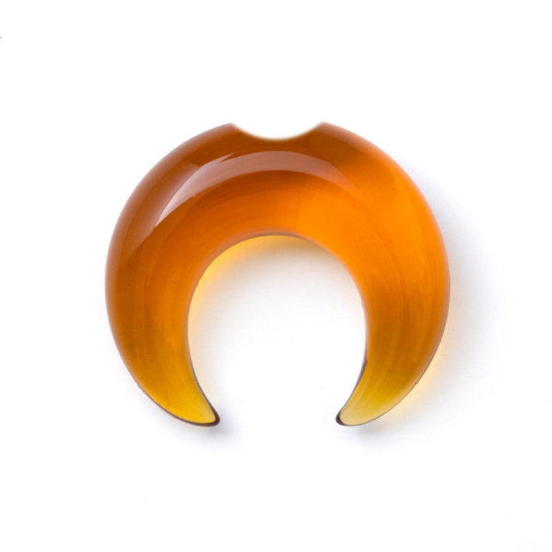 May include: A crescent moon shaped amber glass plug for stretched earlobes.