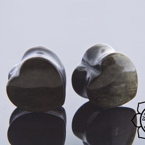 May include: Pair of black heart-shaped stone ear gauges. The gauges have a smooth, polished finish and a subtle shimmer.