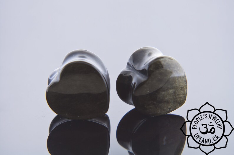 May include: Pair of black heart-shaped stone ear gauges. The gauges have a smooth, polished finish and a subtle shimmer.