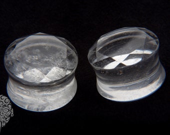 May include: Two clear quartz crystal plugs, each with a faceted design. The plugs are round and have a smooth, polished finish.