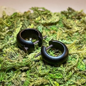 May include: A pair of black wooden hoop earrings. The earrings are simple and elegant, and they would be a great addition to any jewellery collection.