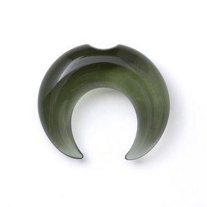 May include: A crescent-shaped green glass ear gauge. The gauge is smooth and polished.