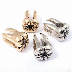 Peut inclure: Quatre bijoux de corps en or et argent en forme de dents. Les bijoux sont conçus pour ressembler à une dent humaine. Les bijoux sont un choix populaire pour les piercings corporels.