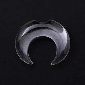 May include: Clear crescent moon shaped glass plug for stretched ears.
