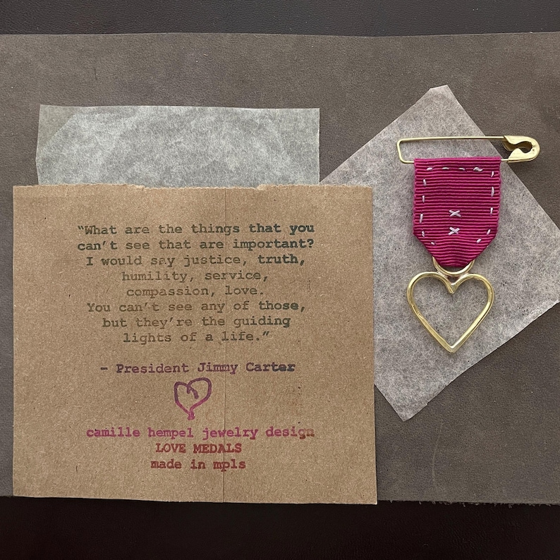 jimmy carter quote values of love and service 
faux-military packaging 
camille hempel design bespoke
 punk love medals with hand sewn ribbon hand wrought brass hearts on safety pins