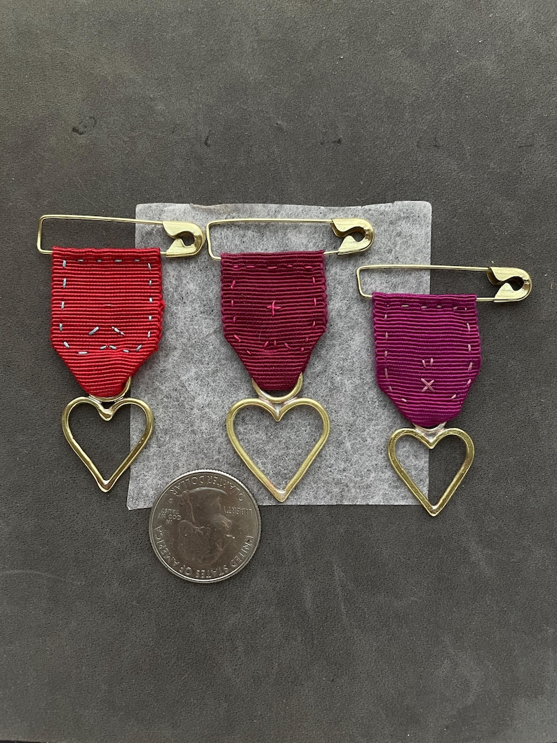 punk heart medals in poppy orange garnet red and raspberry grosgrain ribbon and hand wrought brass hearts by camille hempel design