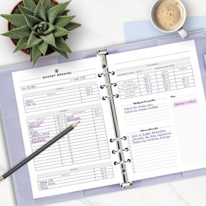May include: A monthly budget planner with a purple cover. The planner has a section for income and expenses, as well as a section for tracking savings goals. The planner is open to the October 2018 page.
