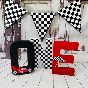 May include: Red, black and white "ONE" letters with a chequered pattern. The letter "O" has a red racing car with the number 29 on it. A chequered flag banner hangs above the letters.