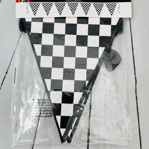 May include: A black and white chequered banner measuring 5.41 feet in length. The banner is packaged in a clear plastic bag with a black ribbon.