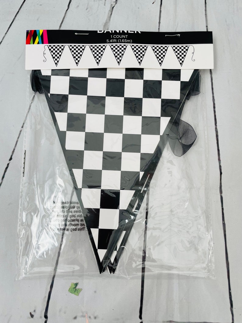 May include: A black and white chequered banner measuring 5.41 feet in length. The banner is packaged in a clear plastic bag with a black ribbon.