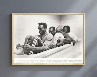 May include: Black and white framed print featuring four men in a bathtub. The men are dressed in athletic wear. The image has text at the bottom. The frame is a light wood color.