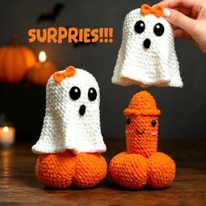 Puede incluir: Dos figuras de fantasmas tejidas a ganchillo en blanco con lazos naranjas y ojos de botón negros, y una figura fálica tejida a ganchillo en naranja con ojos negros y una pequeña sonrisa. El texto SURPRIES!!! es visible en letras naranjas.