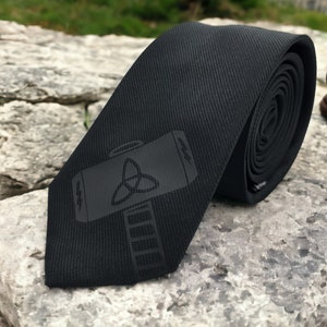 May include: A black tie featuring a dark grey hammer and a triquetra symbol.