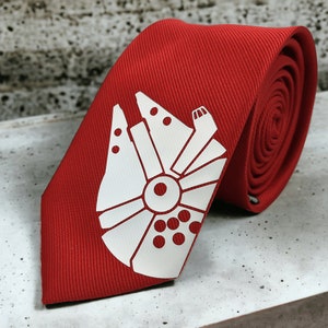 Puede incluir: Una corbata roja con una silueta blanca del Halcón Milenario, la nave espacial de Star Wars.
