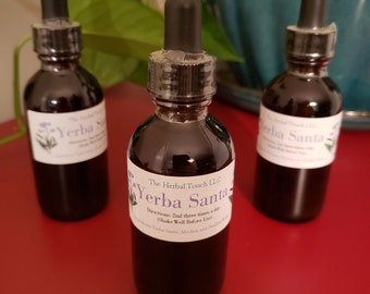 May include: Three brown glass bottles with dropper tops, labeled "Yerba Santa" and "The Herbal Touch LLC". The bottles are sitting on a red surface.
