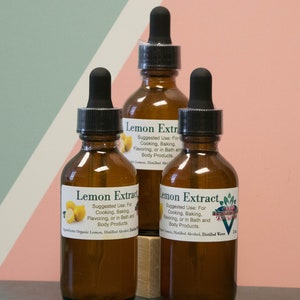 May include: Three amber glass bottles with dropper tops filled with lemon extract. The bottles have white labels with green text that reads "Lemon Extract" and instructions for use. The bottles are sitting on a wooden surface.