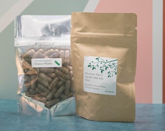 May include: A brown paper bag with a white label that reads "Directions: Take 2 capsules a day with water. Ingredients: Chanca Piedra and Vegan Capsules. 60 Capsules".  A silver bag with a white label that reads "The Herbal Touch LLC Chanca Piedra" and contains brown capsules.