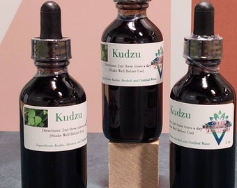 May include: Three dark brown glass bottles with dropper tops, each labelled "Kudzu" and containing a dark liquid. The bottles are sitting on a wooden surface. The label on the middle bottle reads "Directions: 2ml three times a day (Shake Well Before Use)" and "Ingredients: Kudzu, Alcohol, and Distilled Water".