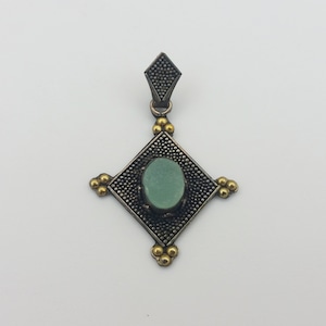 May include: A silver pendant with a green stone set in a square frame with gold accents.