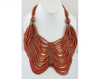 May include: A statement necklace made of orange beads with silver accents. The necklace is layered and has a cascading effect.
