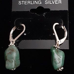 May include: Sterling silver earrings with green turquoise stones. The earrings have a lever back closure.