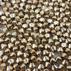 May include: A large quantity of gold-coloured metal beads. The beads are cone-shaped with a small hole at the top.