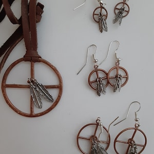 May include: A selection of copper-coloured jewellery with silver feather accents. The set includes a pendant necklace with a leather cord and three pairs of earrings. The earrings and pendant feature a peace symbol design.