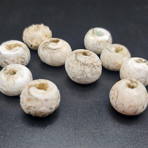 Puede incluir: Una colección de 10 cuentas de cerámica blanca con diseños intrincados. Las cuentas son redondas y tienen un agujero en el centro. Son perfectas para hacer joyas u otros proyectos de artesanía.