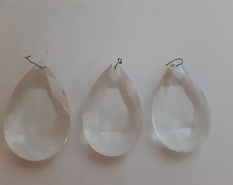 Puede incluir: Tres prismas de cristal transparentes en forma de lágrima con bucles de alambre plateado en la parte superior.